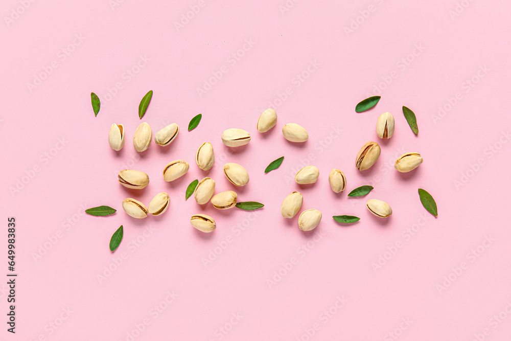 Tasty pistachio nuts and leaves on pink background