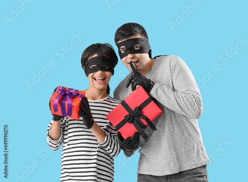 Little boy and his father dressed for Halloween as thieves with gifts on blue background photo