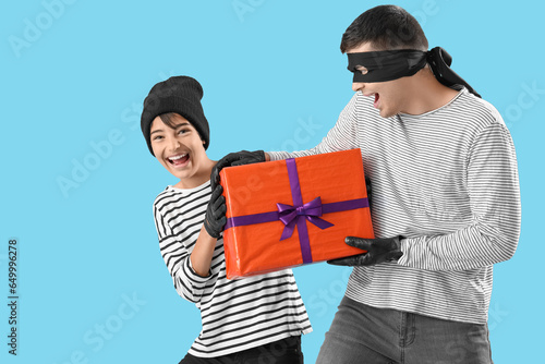 Fotografie Little boy and his father dressed for Halloween as thieves with gift on blue bac