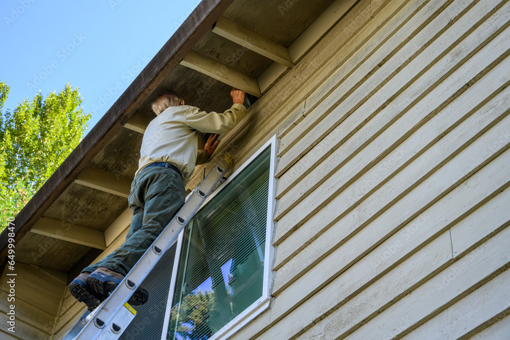 custom made wallpaper toronto digitalSenior man on an extension ladder replacing the mesh of an attic vent on the exterior of a residential building