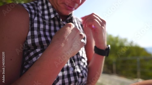 Young happy woman unbuttoning plaid shirt. Side view on female body part in plaid blouse. Close up of unrecognizable woman unbutton her blouse outside in park. Summer Vacation in hot weather concept