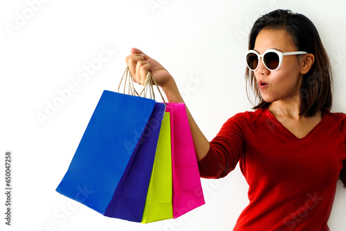 The woman smiles happily and holds colorful shopping bags. She held up the shopping bag. Show happiness in purchasing products