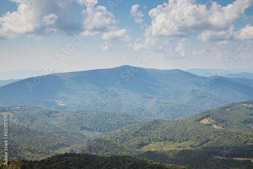 Beautiful view of the Ukrainian Carpathians to the mountains and valleys. Rocky peaks and wood of the Carpathians in late summer. Yellow and green grass  and the top of the mountain and the path to it