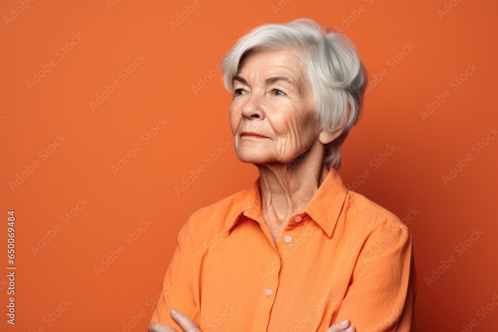 shot of a senior woman standing against an orange background shot of a senior woman standing against an orange background