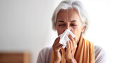 A senior woman manages her runny nose, using a white tissue.