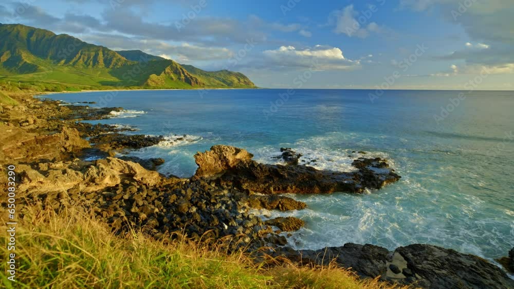 Seascape golden hour lighting view of the ocean in hawaii with vibrant colors and windy grass blowing Seascape golden hour lighting view of the ocean in hawaii with vibrant colors and windy grass blowing