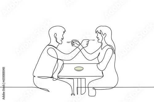 man and woman spoon feeding each other - one line art vector. concept lovers in a cafe or restaurant, metaphor for sharing food, symbiosis, compromise in relationships