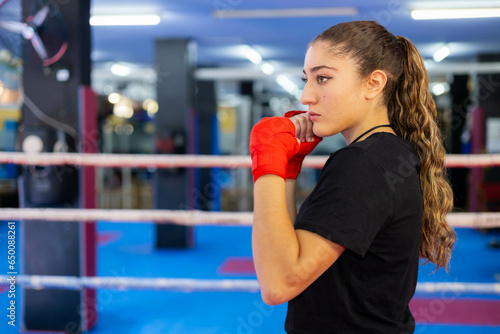 Female boxer portrait in guard position in a ring. Fighting sport training.