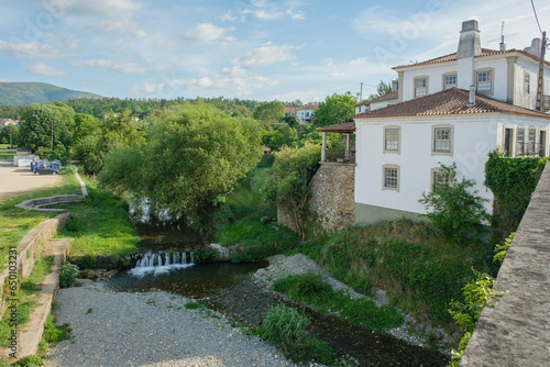 View of a beautiful old house in Coja, Arganil, Portugal, with the water stream and trees by its side photo