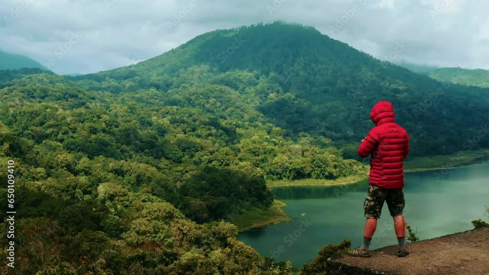Travel people standing on background Lake Tamblingan, one of the twin lakes along with Lake Buyan located in caldera Bedugul Volcano Bali, Indonesia 4K Aerial view Travel people standing on background Lake Tamblingan, one of the twin lakes along with Lake Buyan located in caldera Bedugul Volcano Bali, Indonesia 4K Aerial view