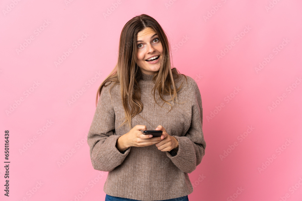 Young slovak woman isolated on pink background surprised and sending a message Young slovak woman isolated on pink background surprised and sending a message