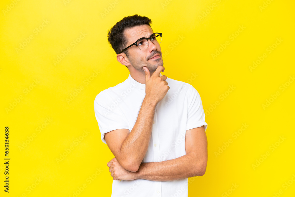 Young handsome man over isolated yellow background having doubts Young handsome man over isolated yellow background having doubts
