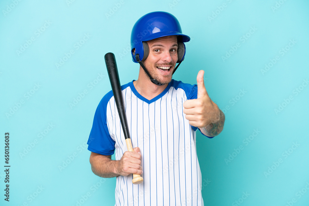 Baseball player with helmet and bat isolated on blue background with thumbs up because something good has happened