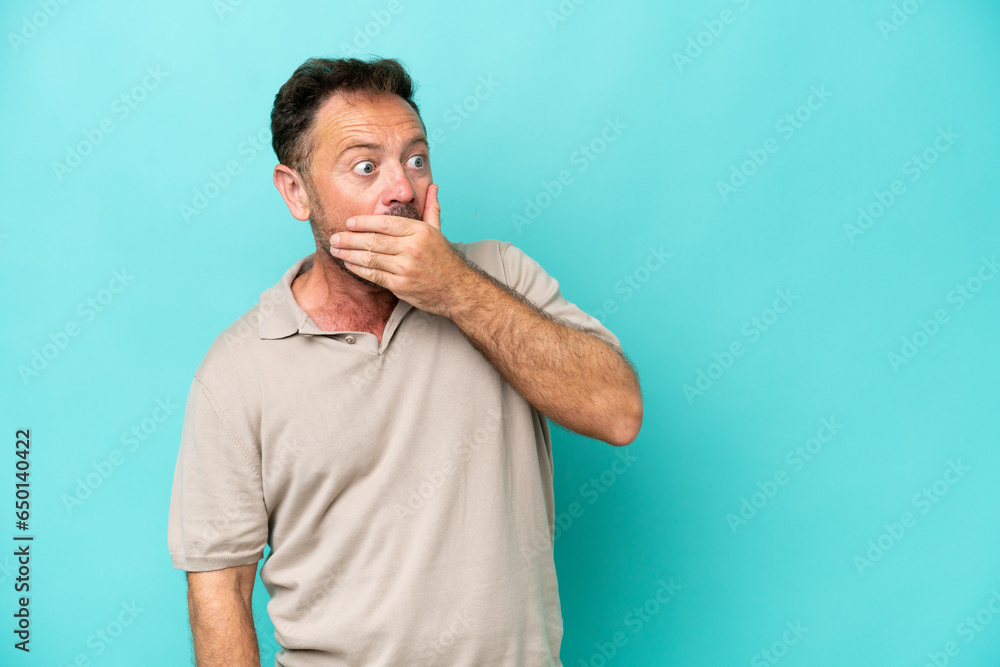 Middle age caucasian man isolated on blue background doing surprise gesture while looking to the side Middle age caucasian man isolated on blue background doing surprise gesture while looking to the side