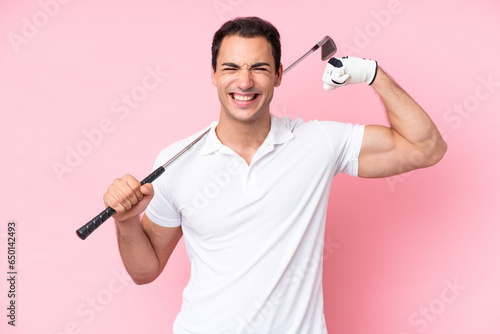 Young golfer player man isolated on pink background doing strong gesture