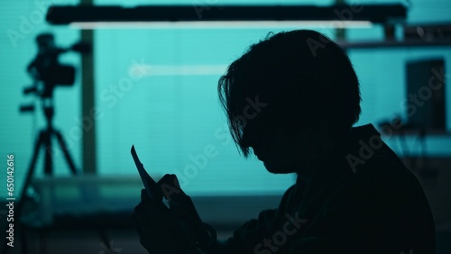 Close up silhouette shot of a suspect, offender, perpetrator or prisoner sitting in the interrogation room. He is studying the evidence in front of him. photo
