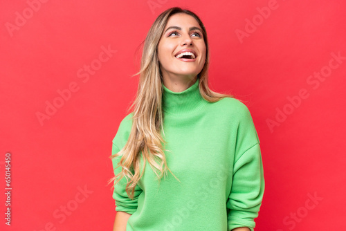 Young Uruguayan woman isolated on red background laughing