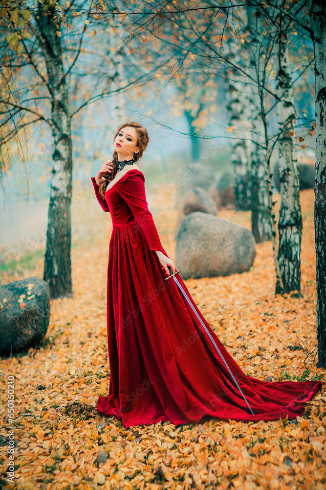 Portrait of magnificent Fashion gothic girl standing in autumn forest .Fantasy art work.Amazing red haired model in claret dress with a sword .Fairytale about young princess-warrior. Portrait of magnificent Fashion gothic girl standing in autumn forest .Fantasy art work.Amazing red haired model in claret dress with a sword .Fairytale about young princess-warrior.