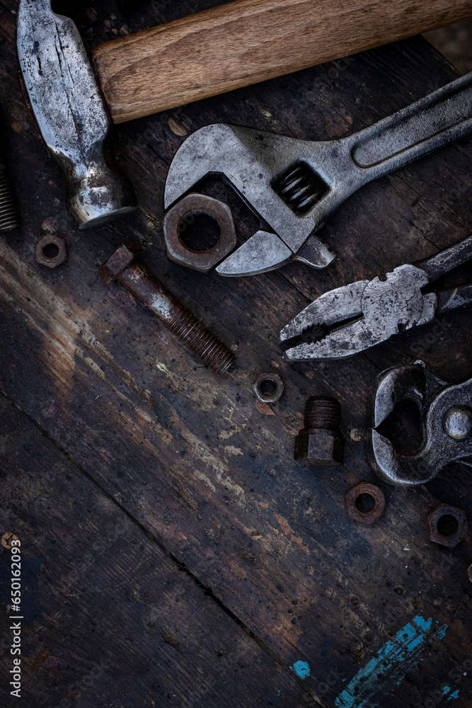 Old work tools nuts, bolts and bearings lie on a wooden workbench Old work tools nuts, bolts and bearings lie on a wooden workbench