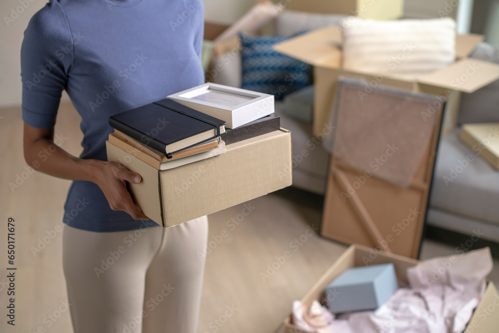 custom made wallpaper toronto digitalYoung woman moving into new apartment holding and unpacking her belongings with cardboard boxes.