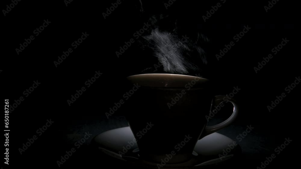 Silhouette of a mug with a warm drink and a fancy curly steam rising up. A steaming coffee cup on a black background. Morning coffee. Silhouette of a mug with a warm drink and a fancy curly steam rising up. A steaming coffee cup on a black background. Morning coffee.
