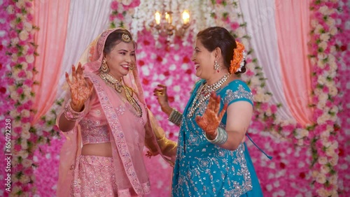 Excited Indian mother With Bridal daughter dancing during wedding stage after marriage - concept of Joyful celebration, happy family and special occasion