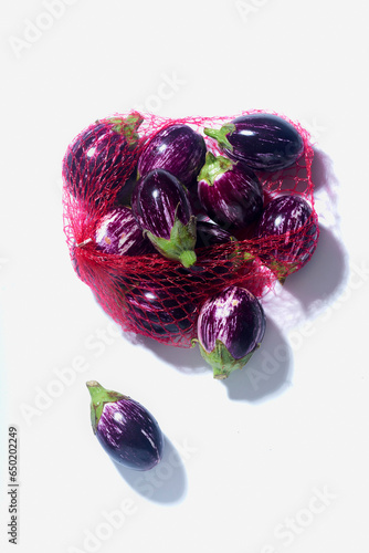 Purple and white striped aubergines in a net photo