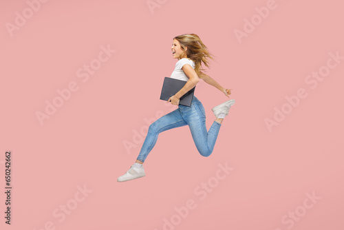 Full body side view young woman jump high work hold a business folder isolated on plain pink background - successful education concept. photo