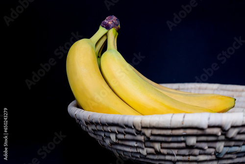 A bunch of Bananas in a wicker basket on a black background (ID: 650243279)