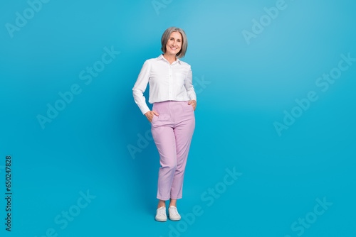 Full size photo of gorgeous cheerful successful person put hands pockets posing empty space isolated on blue color background