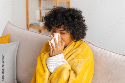Foto Unhappy sick young african american woman with cold sitting on sofa at home