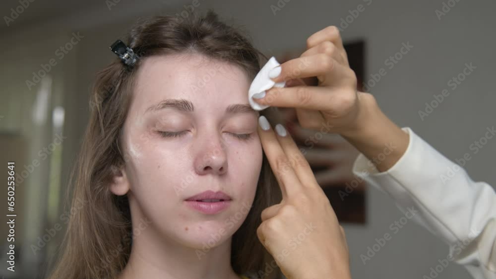 Close-up of preparing eyebrows for eyebrow poking in a cosmetology office. A young Caucasian woman at an appointment with a cosmetologist. Master applies cleanser to client's eyebrows Close-up of preparing eyebrows for eyebrow poking in a cosmetology office. A young Caucasian woman at an appointment with a cosmetologist. Master applies cleanser to client's eyebrows