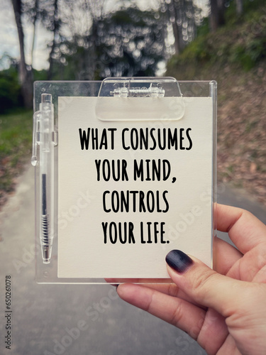 Motivational and inspirational wording. What Consumes Your Mind, Controls Your Life written on a notepad. With blurred styled background.
