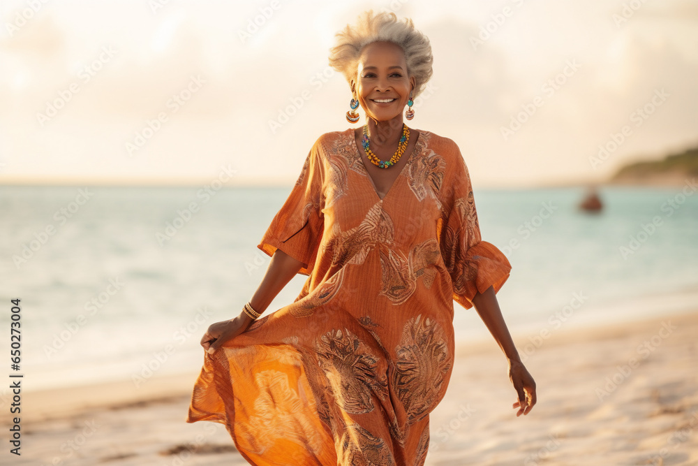 A senior old beautiful african american woman is walking on the sand with a dress on a tropical beach with a calm ocean - autumn weather beach relaxing - obrazy, fototapety, plakaty 