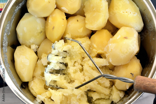 Ziemniaki ugotowane w garnku, rozgniecione tłuczkiem © Hanna