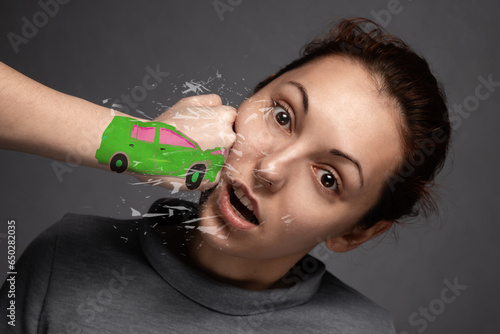 the concept of car accidents, insurance claims . close-up of the accident.The girl is hit by a green car .a punch in the face of a young girl .Fist in the form of drawn machines.close -up photo