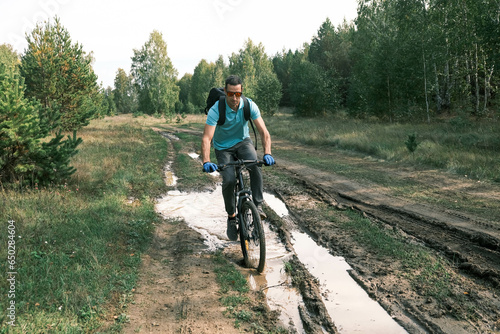 Travel by bike.A man with a backpack and glasses rides a mountain bike through a puddle.An active lifestyle.Mountain Bike