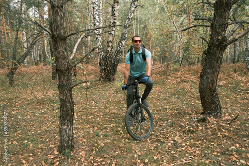 man with a backpack and gloves rides a mountain bike through the forest in autumn.An active lifestyle.Mountain Bike
