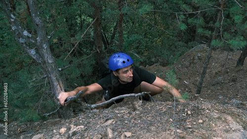 Fototapeta Naklejka Na Ścianę i Meble -  climber in a protective helmet climbs a mountain in the forest.Healthy, active lifestyle