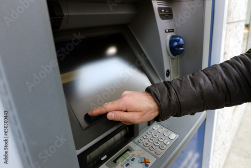 Hand and fingers of a bank customer using the touch screen of ATM automated teller machine  to complete a transaction