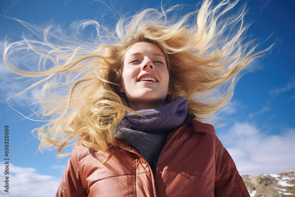 Portrait of young smiling woman with flying blonde hair in windy day standing at mountain - carefree woman Portrait of young smiling woman with flying blonde hair in windy day standing at mountain - carefree woman