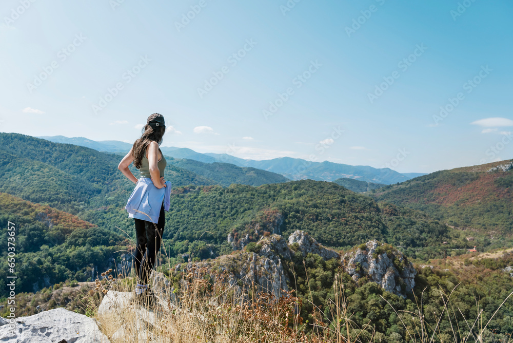 Woman standing in the  summer mountain with stunning view 