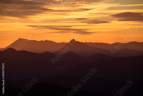 Mountain ridge under cloudy bright sunset sky