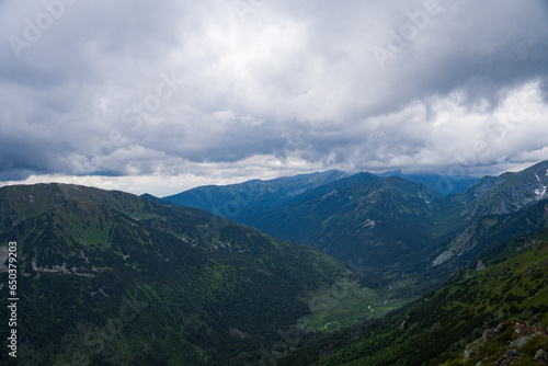 View of mountain peaks in Poland, puffy clouds over the peaks, green mountain slopes