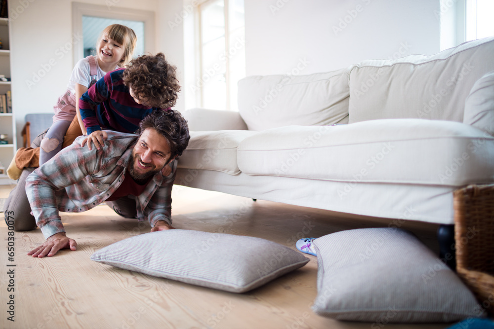 Young father playing with his children in the living room at home