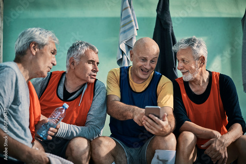 Group of seniors using a smartphone in a locker room after playing football
