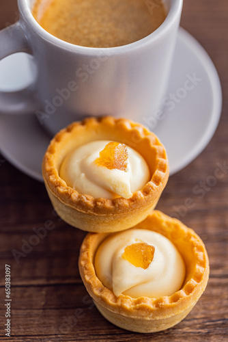 Sweet tarlets. Tasty mini tarts. Mini pie with cream and coffee cup  on kitchen table. photo