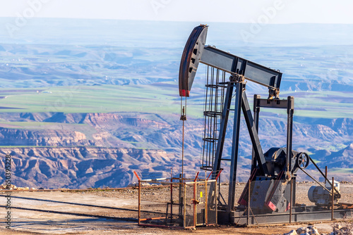 View of the pumpjack in the oil well of the oil field. Arrangement is commonly used for onshore wells producing little oil. It is overground drive for a reciprocating piston pump in an oil well. photo