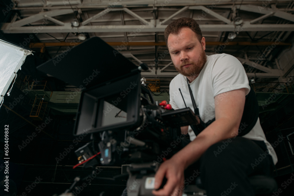 Director of photography with a camera in his hands on the set. Professional videographer at work on filming a movie Director of photography with a camera in his hands on the set. Professional videographer at work on filming a movie