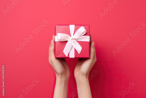 A woman's hands holding a red gift box with a white bow created with Generative AI technology photo